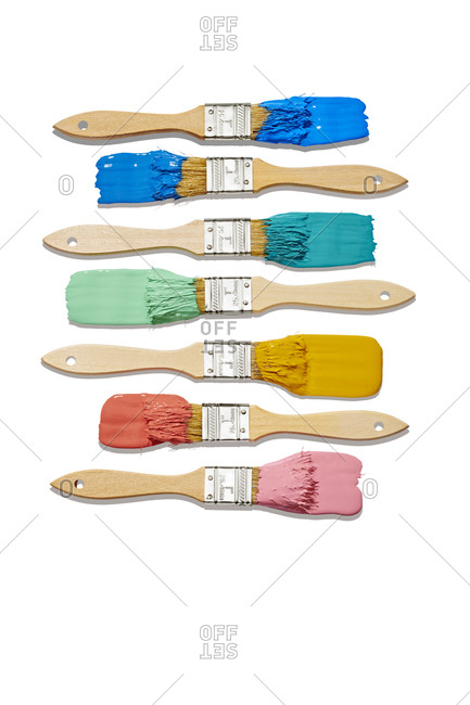 Multiple Paintbrushes with Colorful Paint Organized on White Background