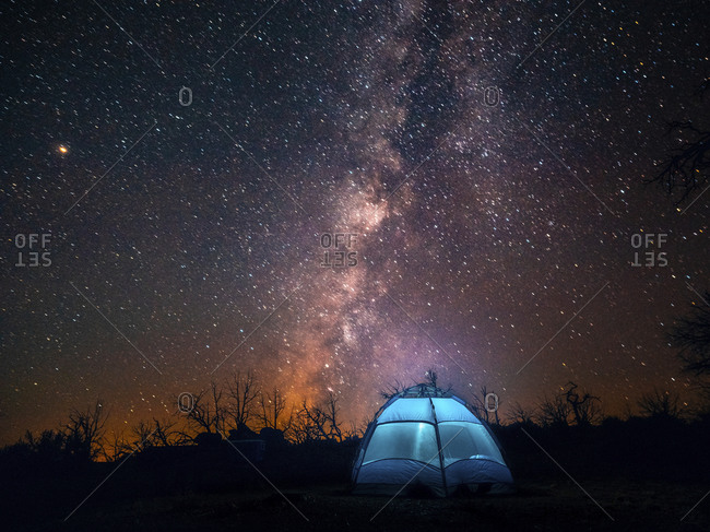 USA, California, Mojave Desert. An illuminated tent against a starry sky and the Milky Way.