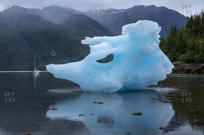 USA, Alaska, Gulf 32 Pilothouse sailboat at anchor near large icebergs from LeConte Glacier grounded at low tide in LeConte Bay on summer evening