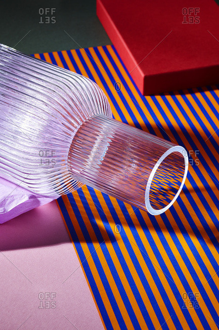 Glass vase lying on colorful striped paper