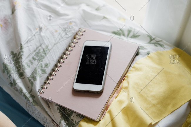 Smart phone on note pad over pillow in bedroom