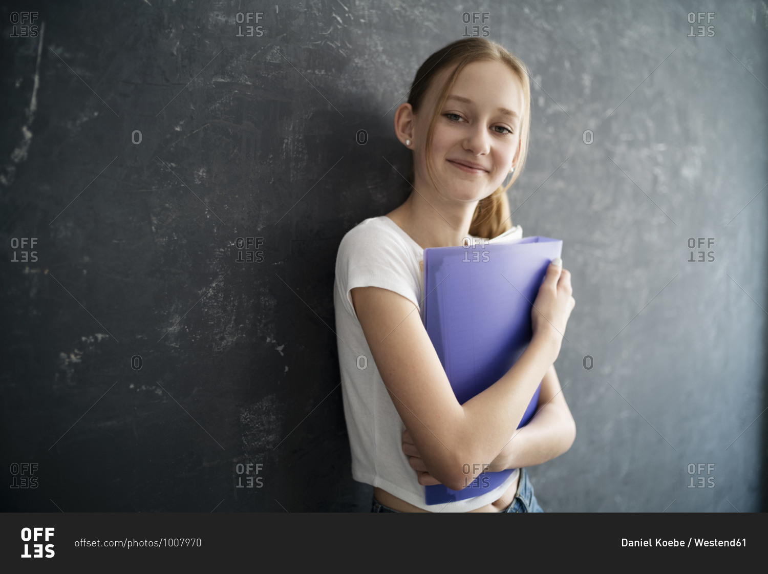 Girl with exercise books in front of black wall