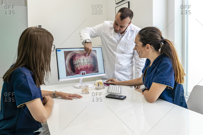 Dentist discussing with female doctors discussing while looking at x-ray in clinic
