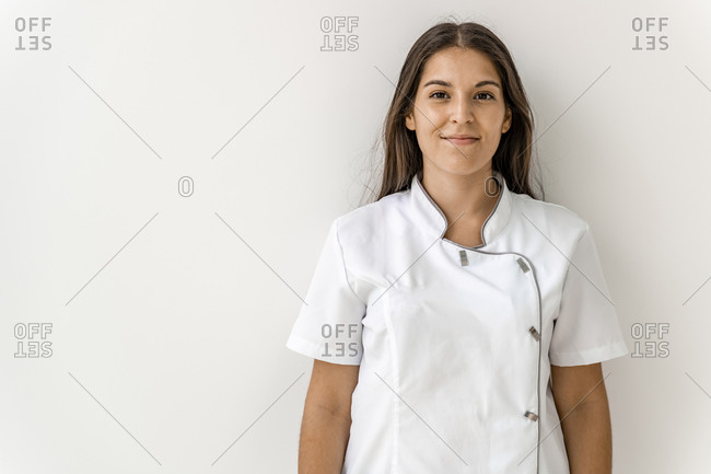 Smiling female nurse against wall in dentist's clinic
