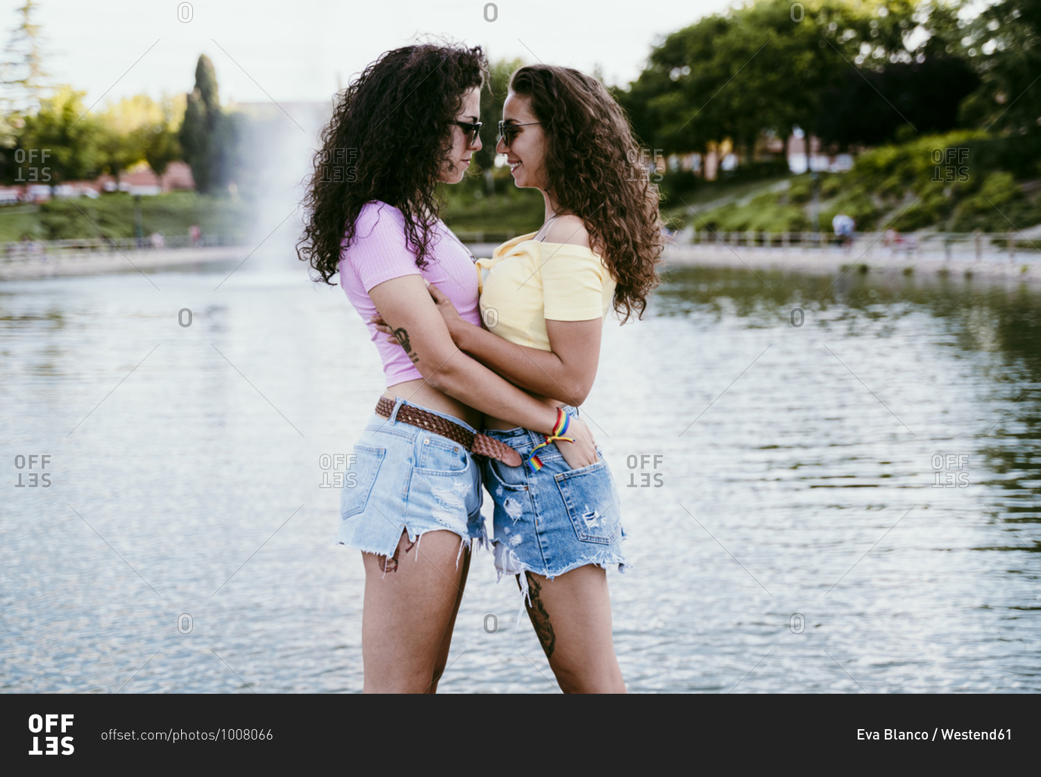 Lesbian couple wearing sunglasses with face to face standing against lake