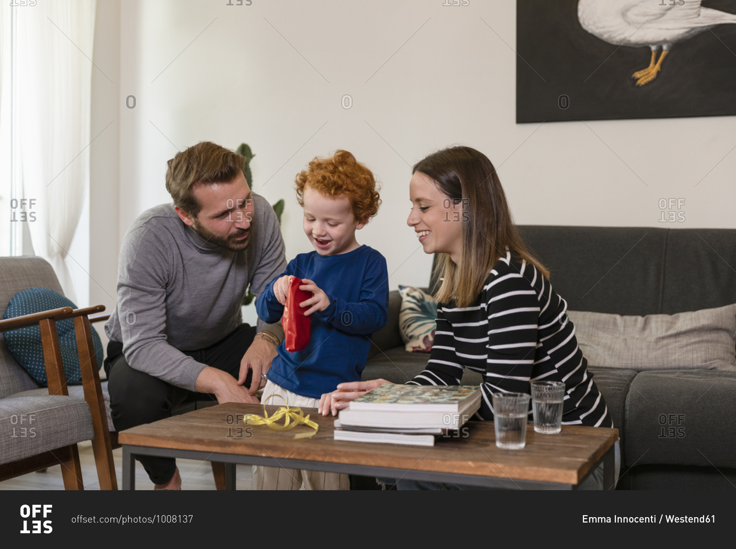 Cute boy showing toy robot to smiling parents in living room at home
