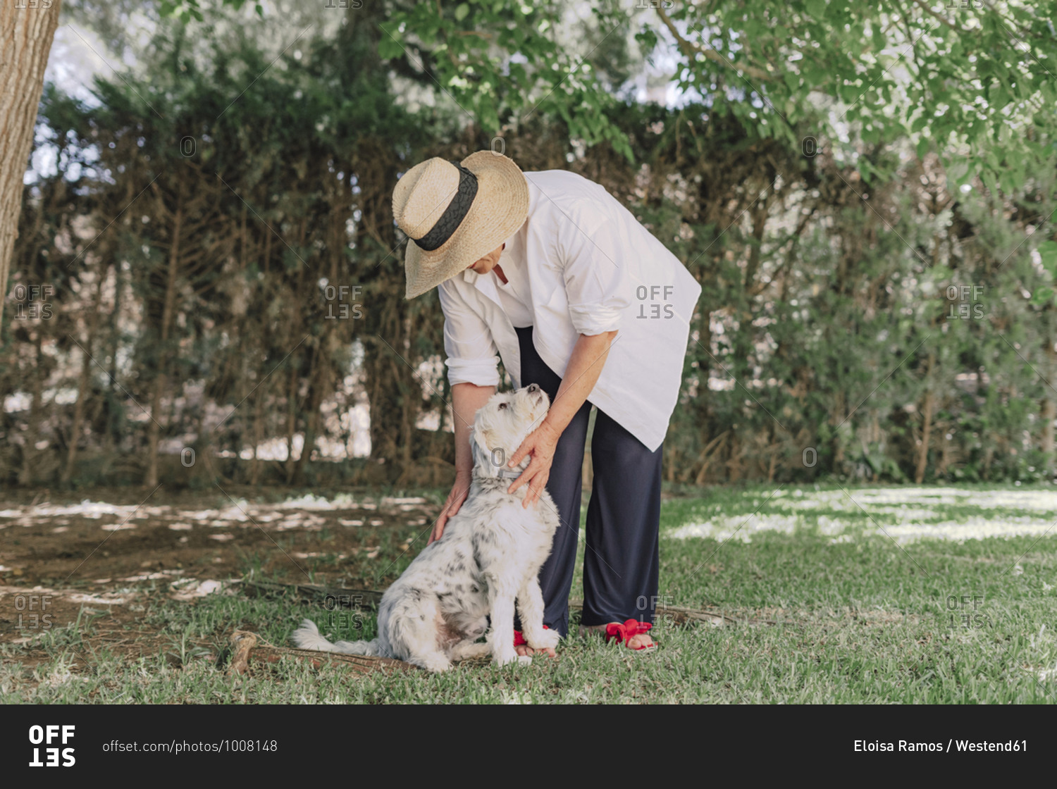 Senior woman wearing hat with dog standing on grassy land in yard