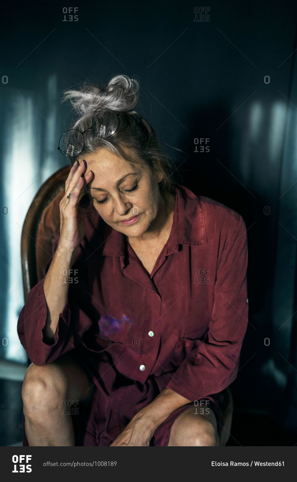 Sad Senior Woman With Head In Hand Sitting On Chair At Home Stock Photo ...