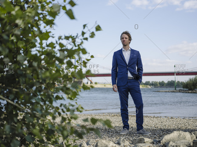 Thoughtful Businessman looking away while standing against Rhine river