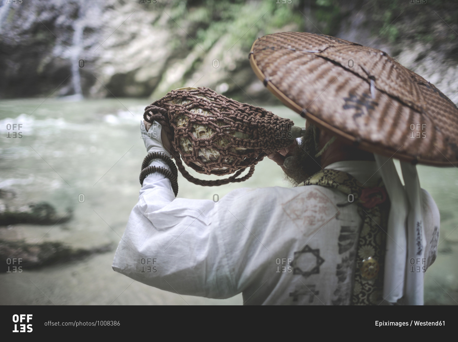 European yamabushi monk in traditional shugendo robe blowing the horagai conch horn