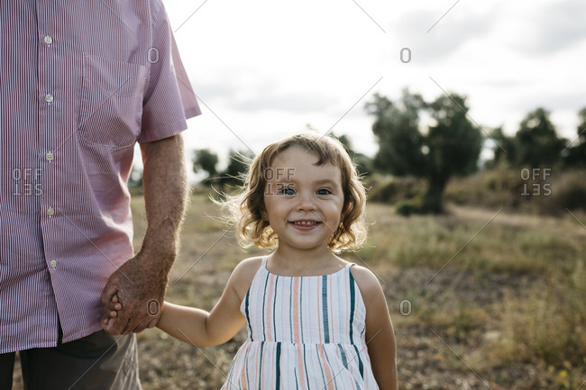 Smiling cute girl holding grandfather's hand while standing on land