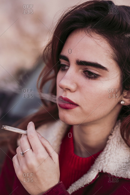 Close-up of thoughtful beautiful woman smoking cigarette