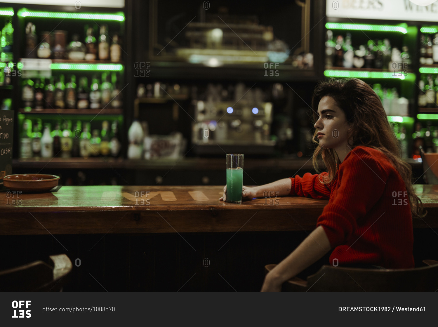 Thoughtful woman with drink on bar counter sitting in restaurant