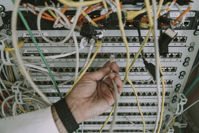 Close-up of hand plugging in cable in data center rack