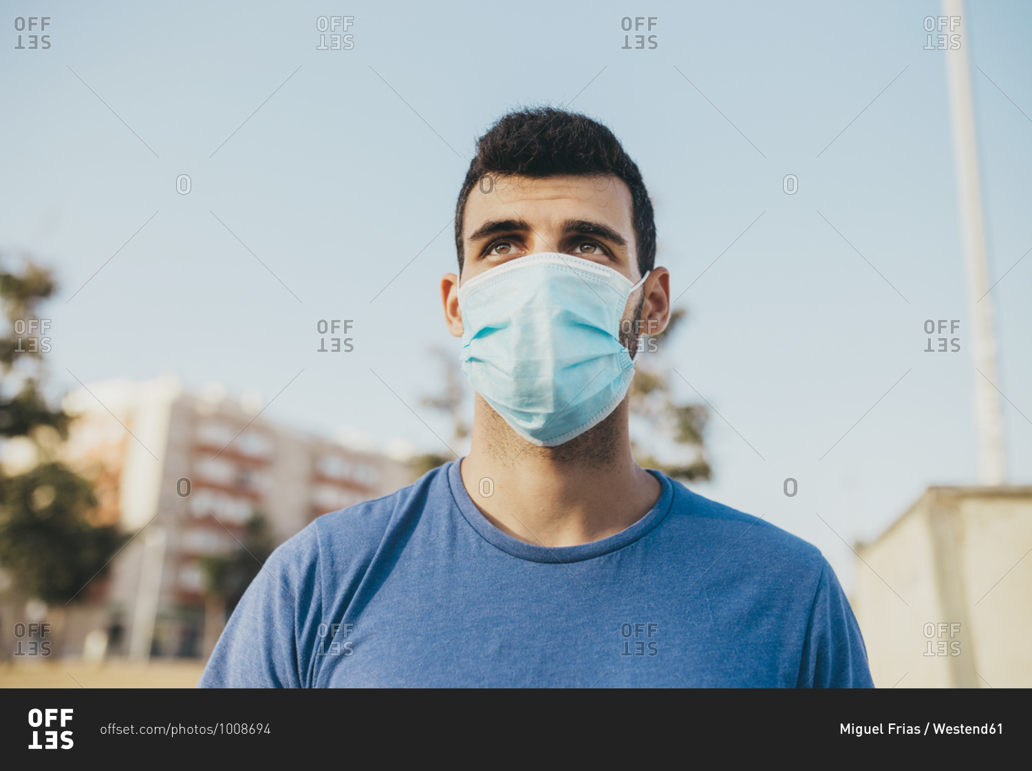 Close-up of thoughtful young man wearing mask against clear sky in city