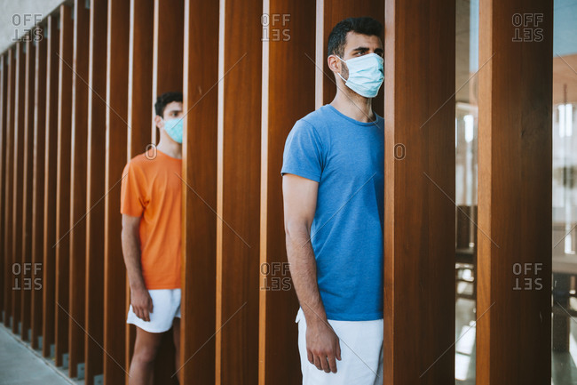 Young men wearing masks standing by wooden built structure in city