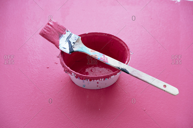Studio shot of paintbrush on top of bucket with pink paint