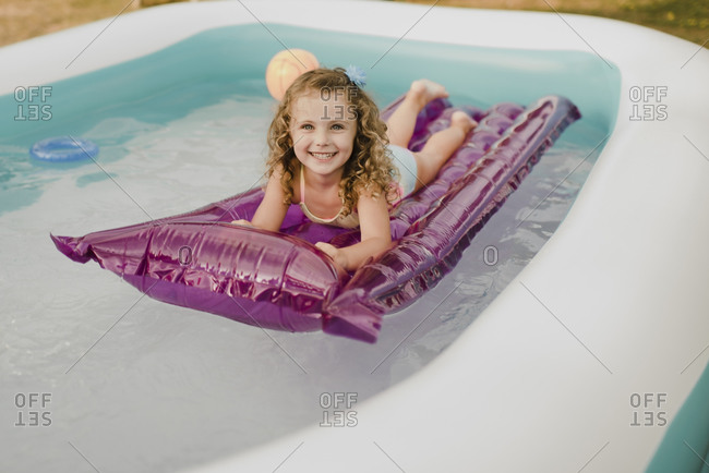 Portrait of a happy girl on airbed in an inflatable swimming pool