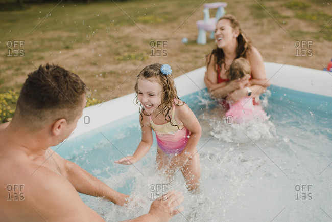 Happy family in an inflatable swimming pool in garden