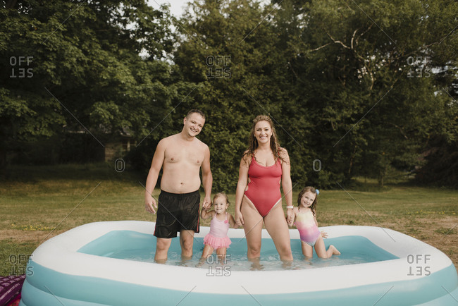 Portrait of a happy family in an inflatable swimming pool in garden