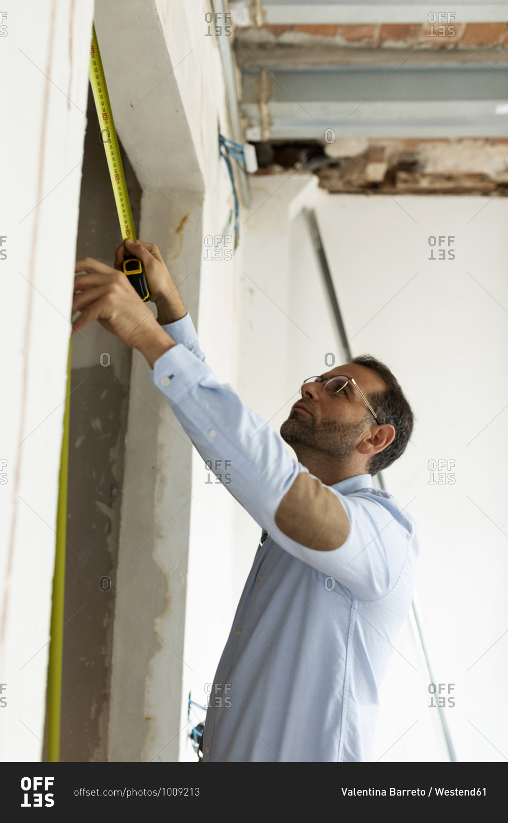 Architect using tape measure in a house under construction