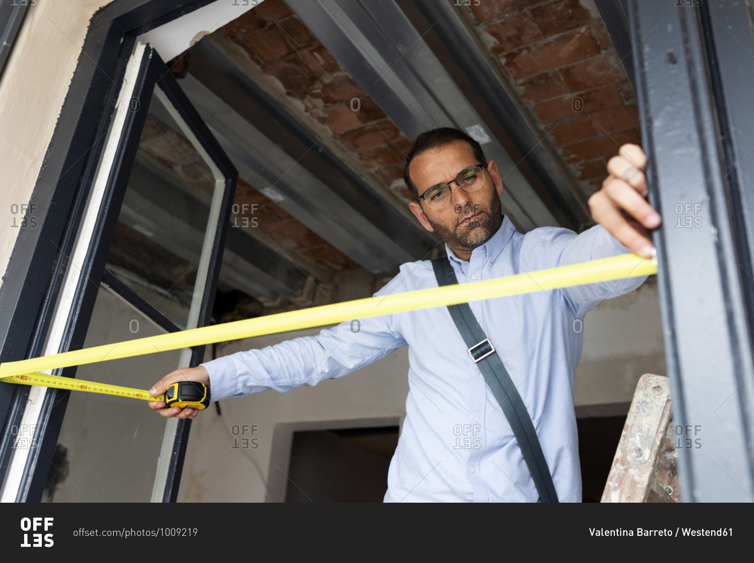 Architect using tape measure on window frame in a house under construction