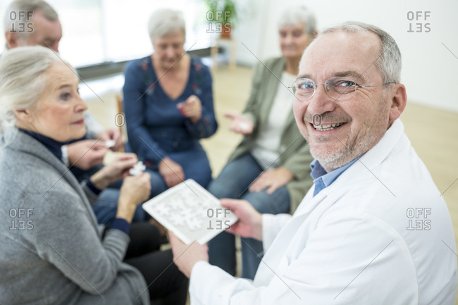 Doctor playing jigsaw puzzle with group of seniors in retirement home