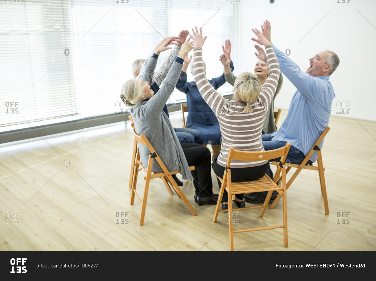 Group of seniors practicing chair gymnastics with instructor in retirement home
