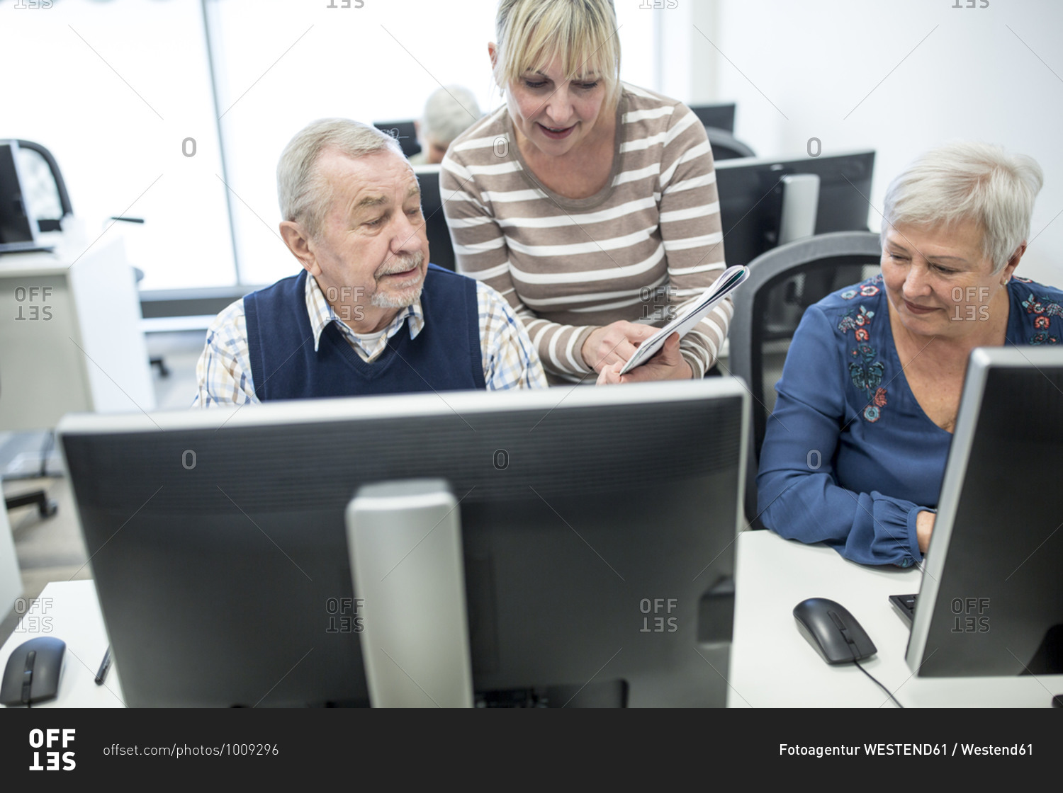 Active seniors attending computer course- instructor giving advice