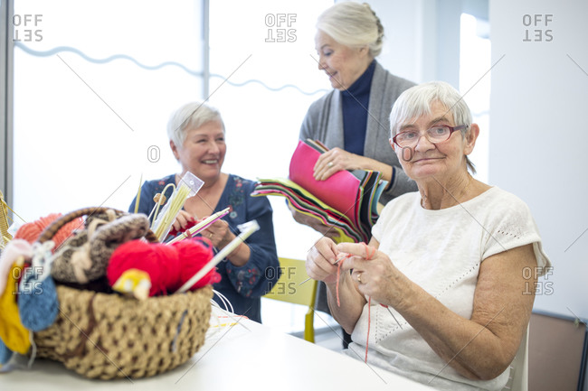 Senior women knitting together in needlework group of retirement home