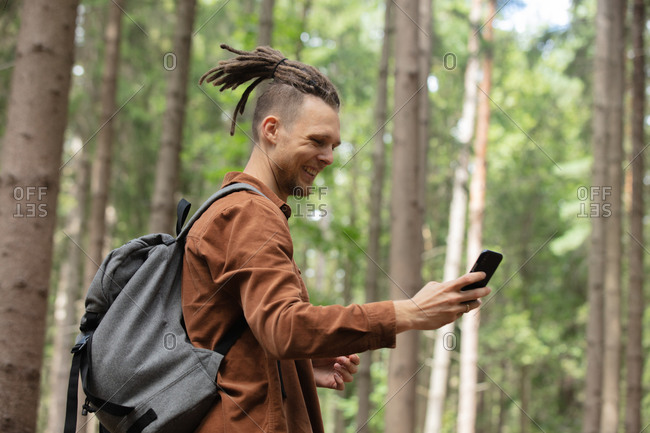 Young man with a mobile phone in the forest