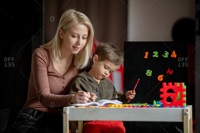 Mother and son draw and color on the table at home