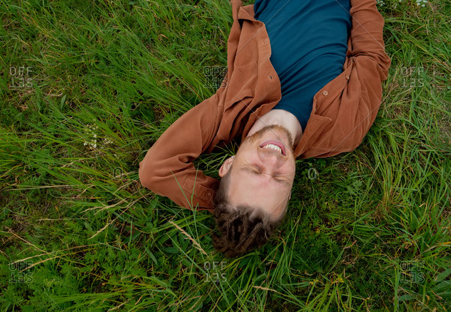 Young guy relaxing and lying on the grass