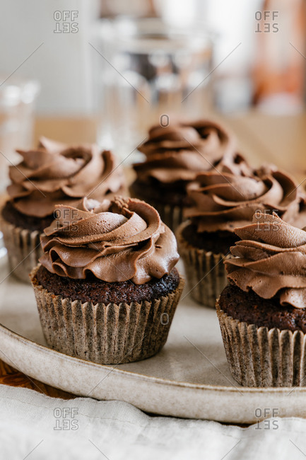 Appetizing sweet chocolate cupcakes with chocolate butter cream served on round tray on table