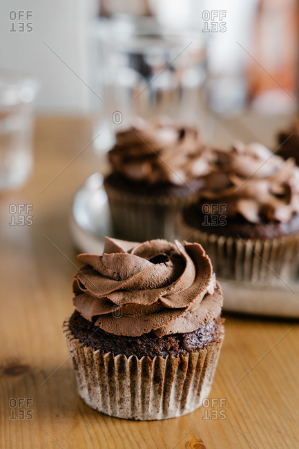 Appetizing sweet chocolate cupcakes with chocolate butter cream served on round tray on table