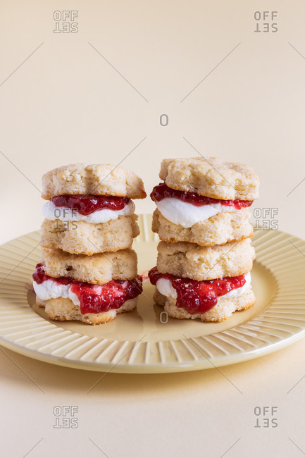 Appetizing homemade sweet scones with berry jam and whipped cream served on plate