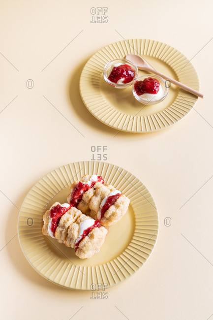Appetizing homemade sweet scones with berry jam and whipped cream served on plate