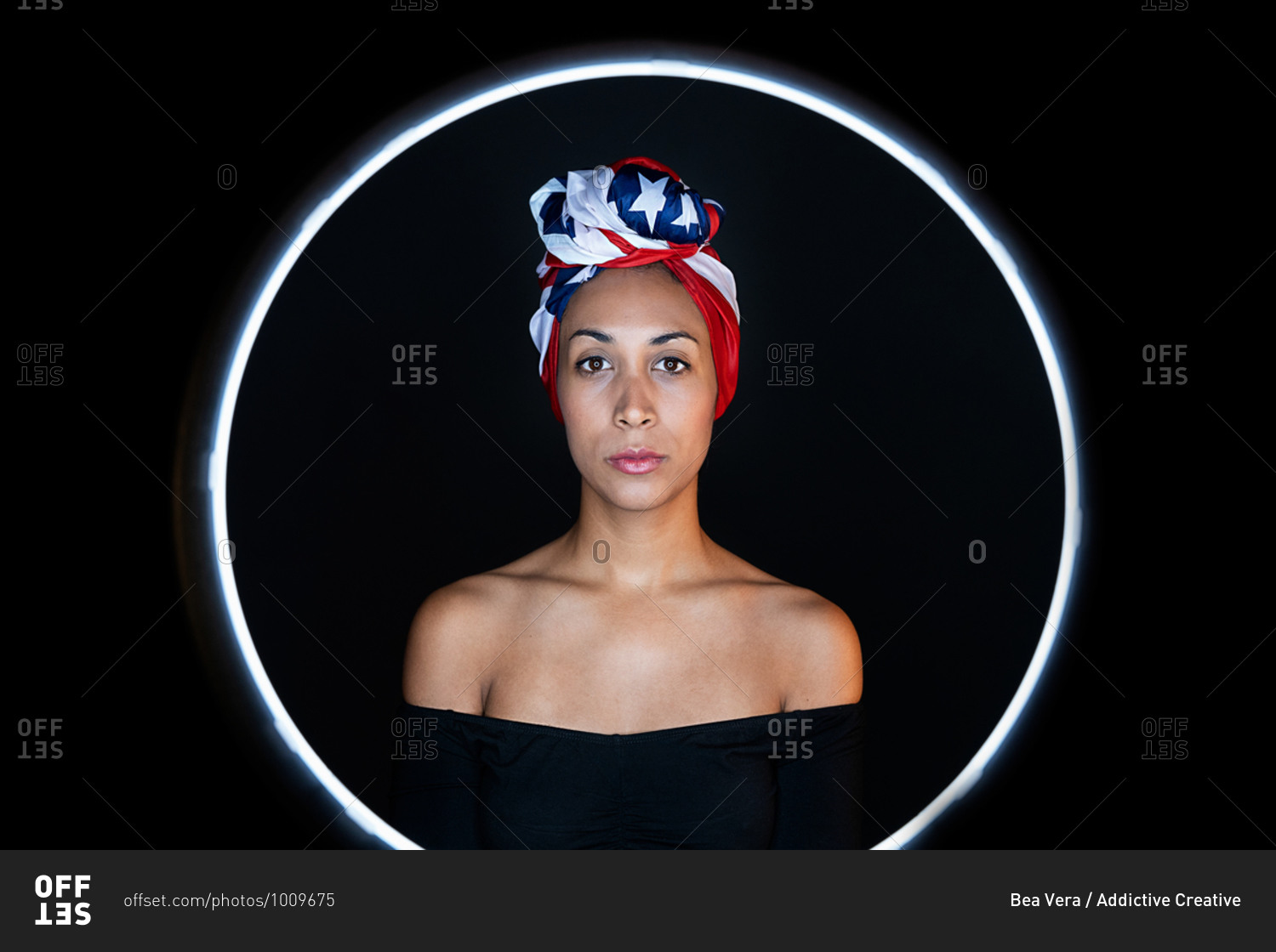 Portrait of a thoughtful black female framed on a led ring wearing proudly the United States of America colors as a head wrap looking at camera