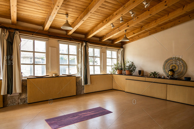 Yoga mat placed on wooden floor inside spacious pavilion decorated in oriental style located in tropical country