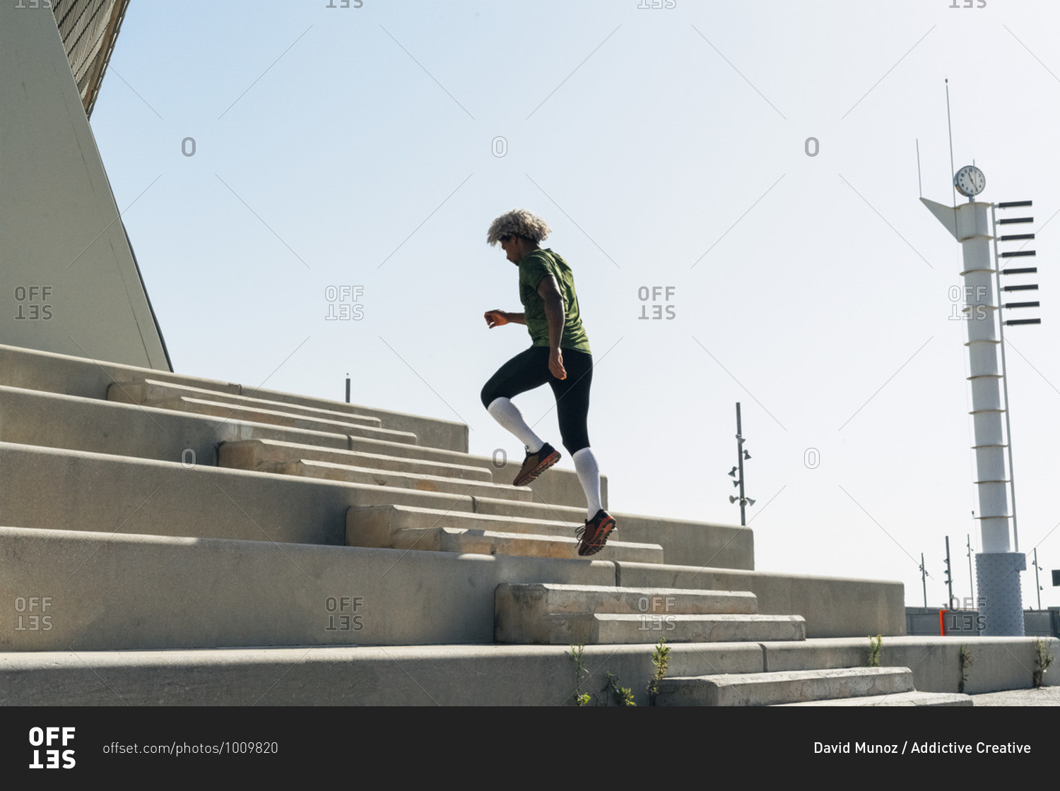 Back view of African American athlete in sportswear running up stairway of modern building during fitness workout in city