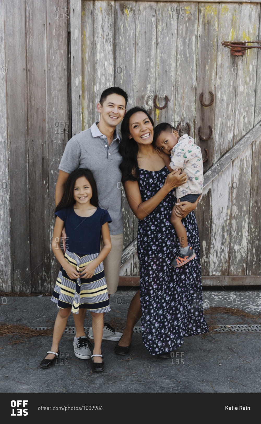 Mom and dad with daughter and toddler boy in front of an old wooden barn