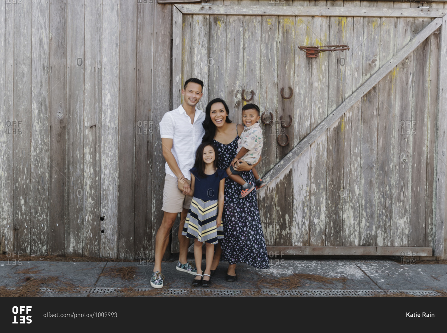 Portrait of a beautiful family standing together in front of an old wooden barn