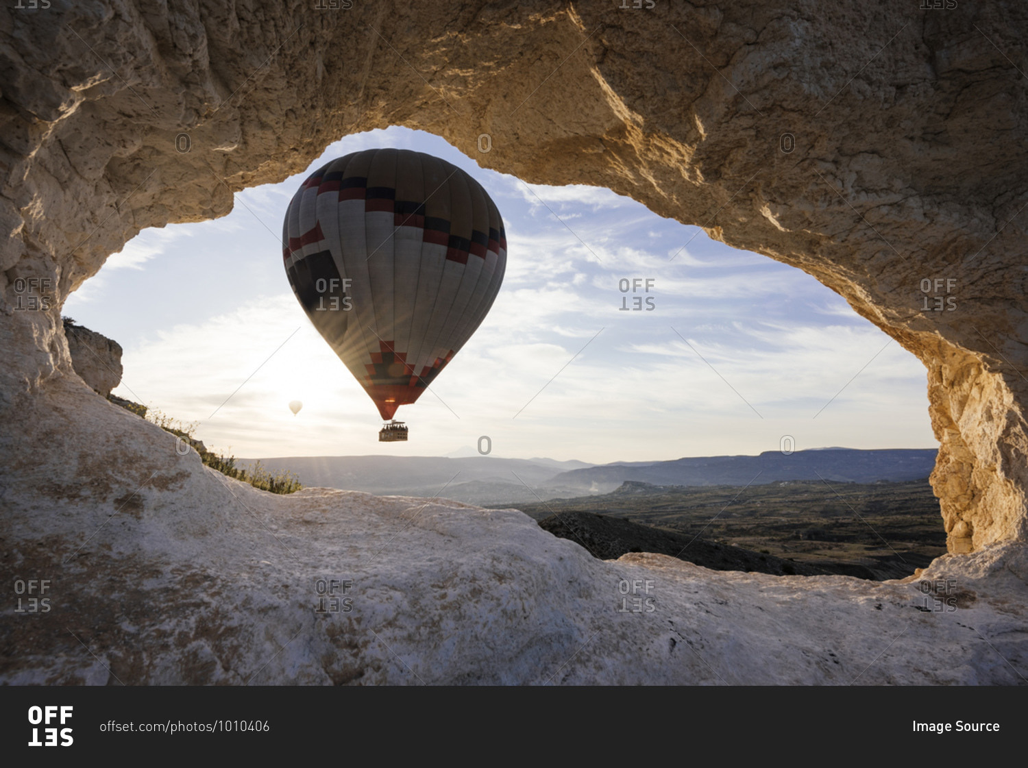 Hot air balloon framed between rock formation at sunrise, Goreme National Park, Cappadocia, Anatolia, Turkey