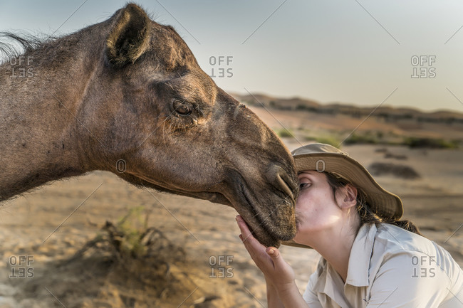 Young woman kissing camel, Abu Dhabi, UAE