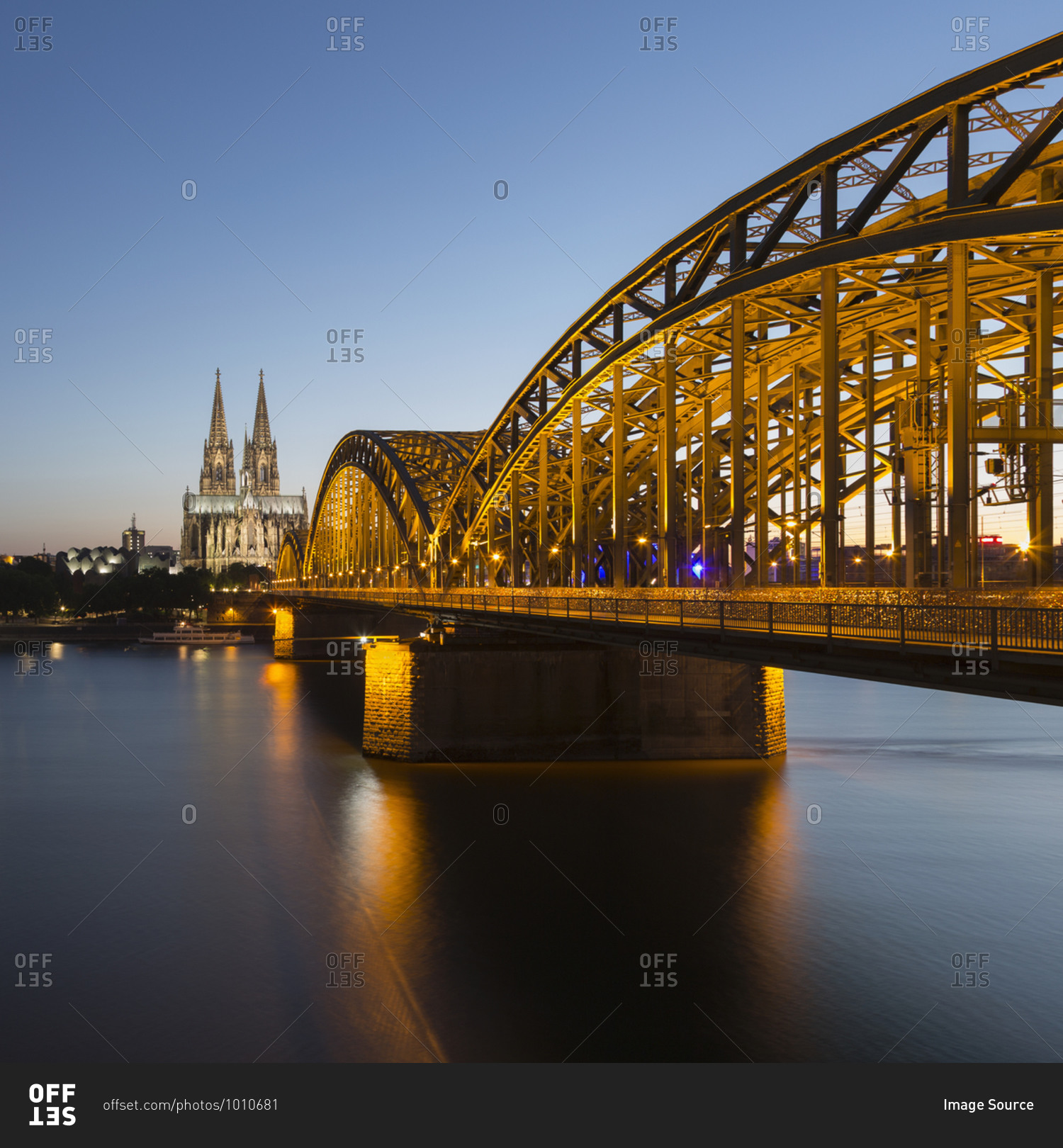 View of Cologne Cathedral (Koelner Dom) and Hohenzollern Bridge (Hohenzollernbruecke) crossing Rhine River at dusk, Cologne, Germany