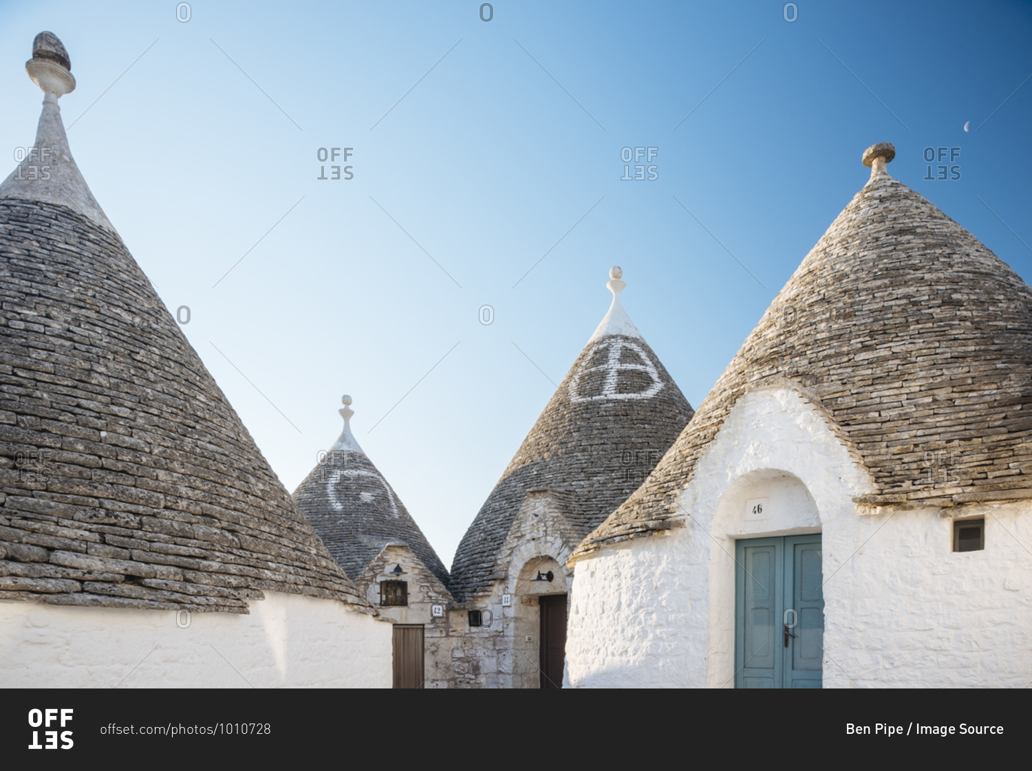 Four whitewashed trullo houses with conical roofs, Alberobello, Puglia, Italy