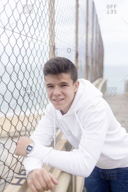 Handsome young guy smiling and leaning on a railing outdoors