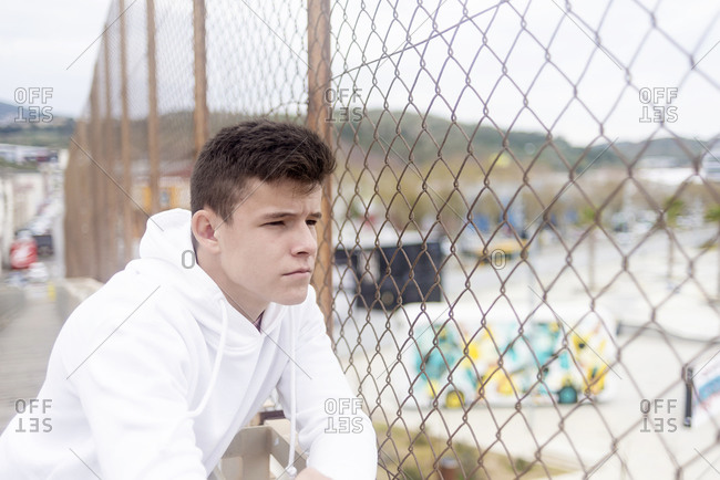 Serious young boy leaning on a railing outdoors
