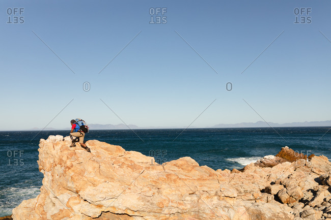 A fit, disabled mixed race male athlete with prosthetic leg, enjoying his time on a trip to the mountains, hiking, climbing on the rocks by the sea. Active lifestyle with disability.