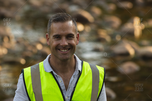 Portrait of happy Caucasian male conservation volunteer cleaning up river in the countryside, smiling to camera. Ecology and social responsibility in rural environment.